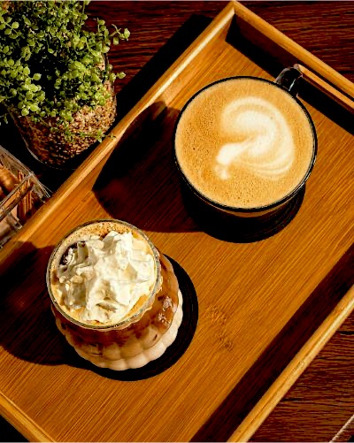 Hot latte and iced signature coffee on a wooden tray