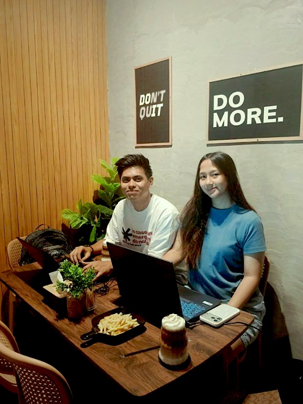 Two customers on laptops under the Do More prints