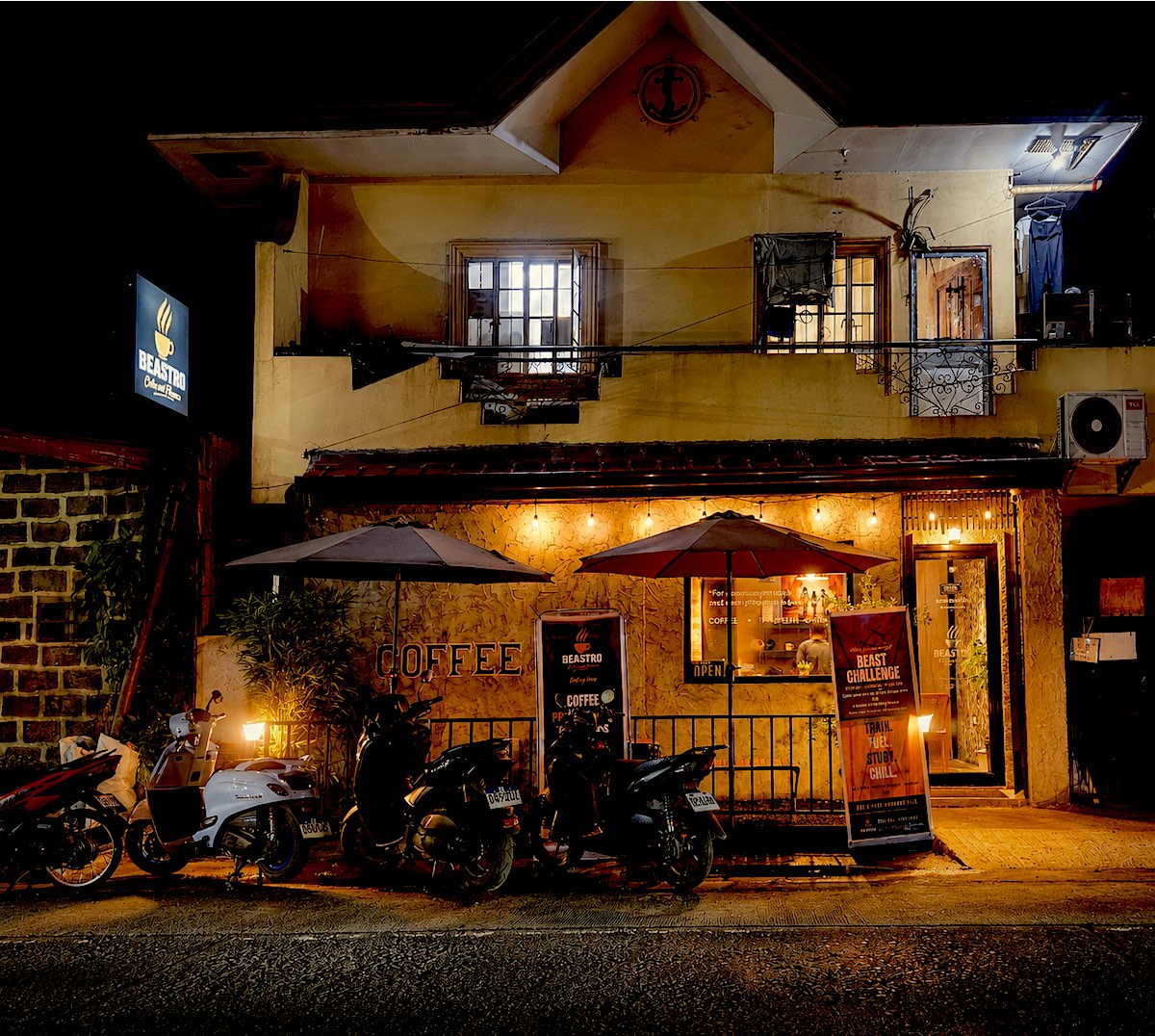 Beastro storefront at night with string lights, umbrellas and the lit sign