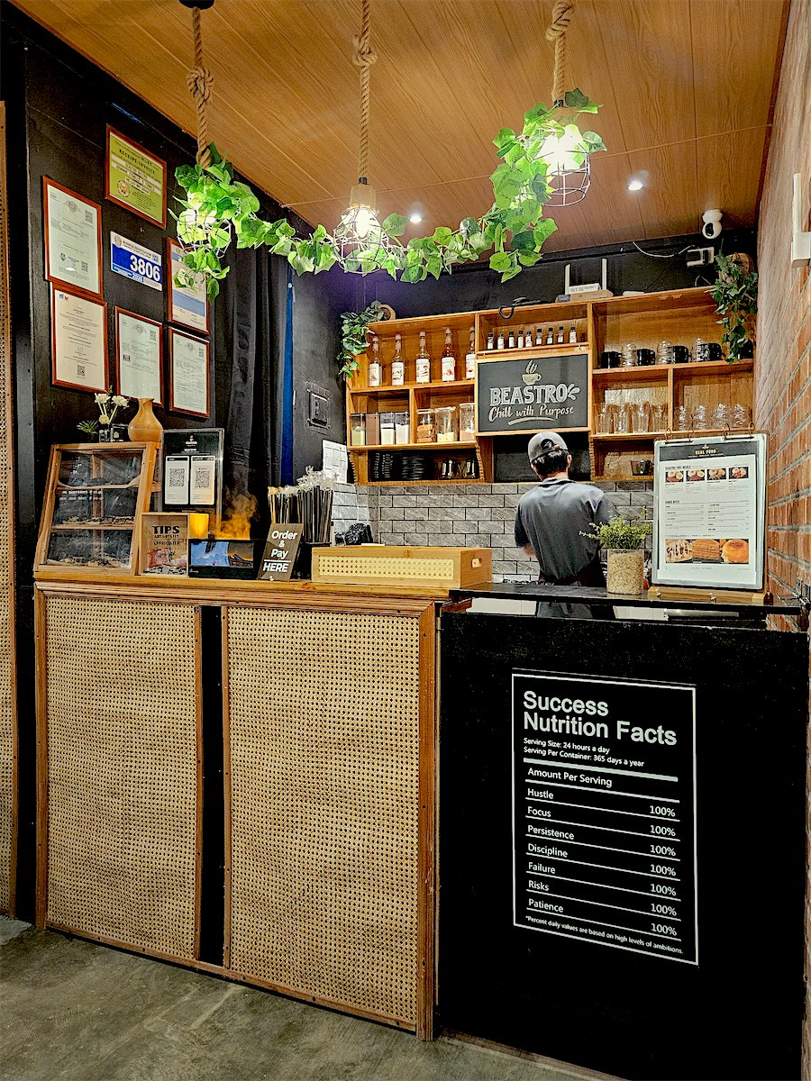 The coffee counter with rattan panels, plants and the Success Nutrition Facts sign