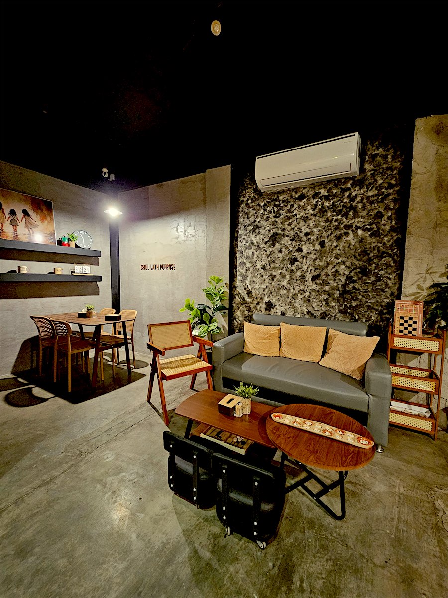 The lounge with a grey sofa, stone wall and wooden tables